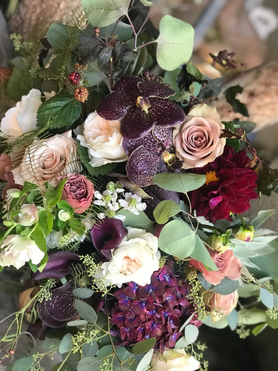 Burgundy, blush, cream, and purple wedding bouquet with loose greenery.
