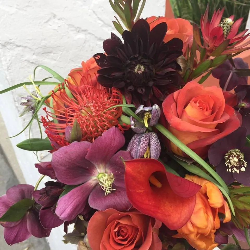 Burgundy, orange, and peach floral arrangement with sculptural flowers.