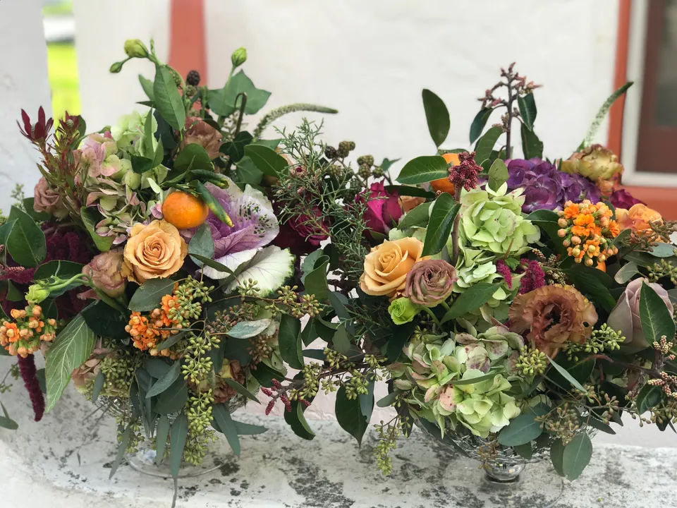 Long garden style table arrangement with warm color, greenery, and seasonal texture.