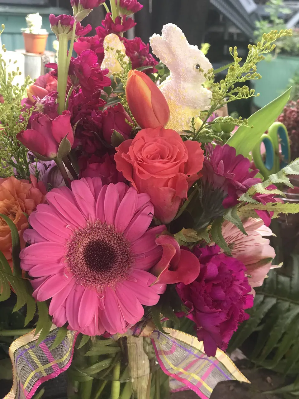 Hot pink and coral garden bouquet with gerbera, roses, orchids, and tropical greenery.
