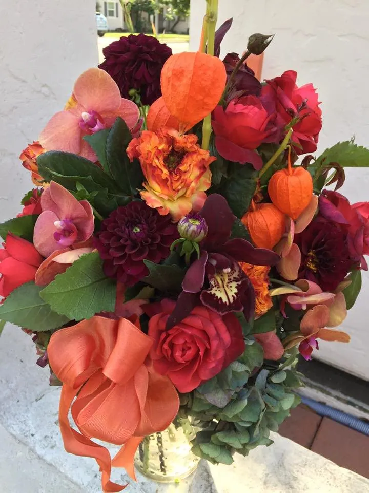 Orange orchid and rose arrangement with vivid warm color.