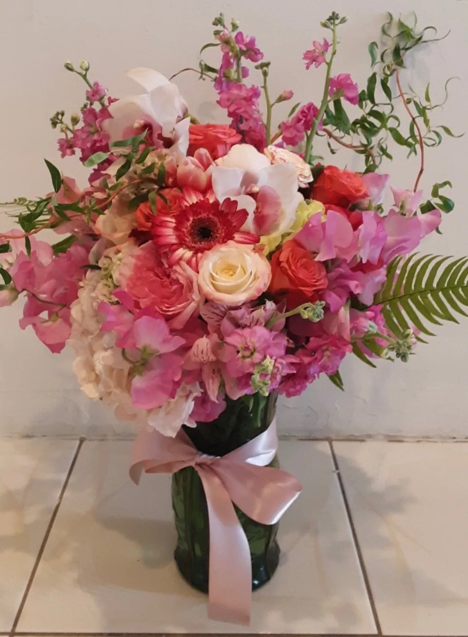 Pink vase arrangement with coral, blush, and hot pink flowers and loose branching line.