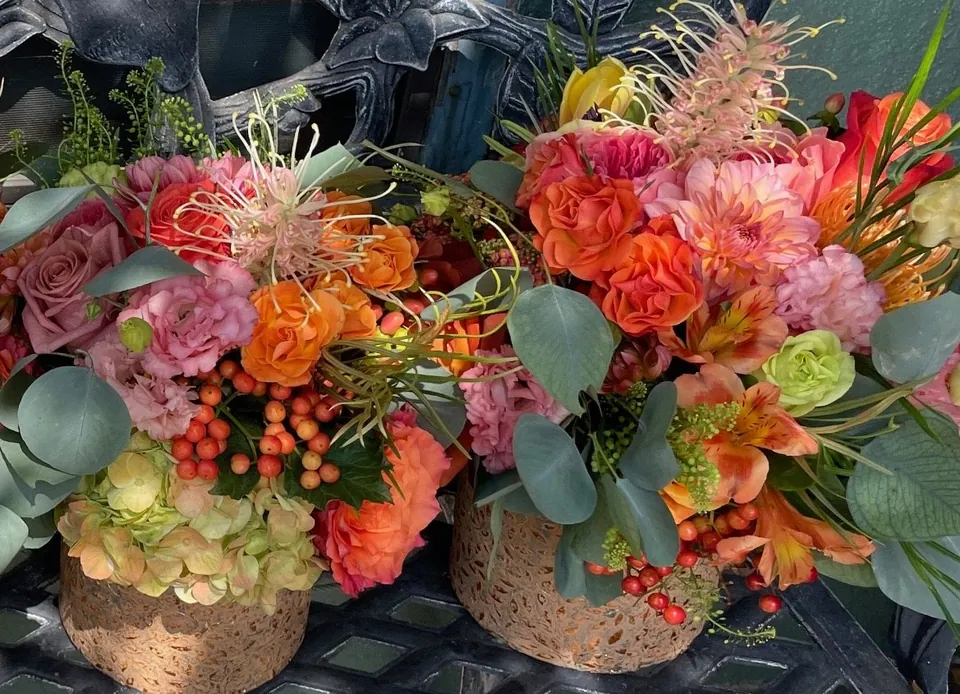 Warm orange, coral, and pink floral vessels arranged in a colorful pair.