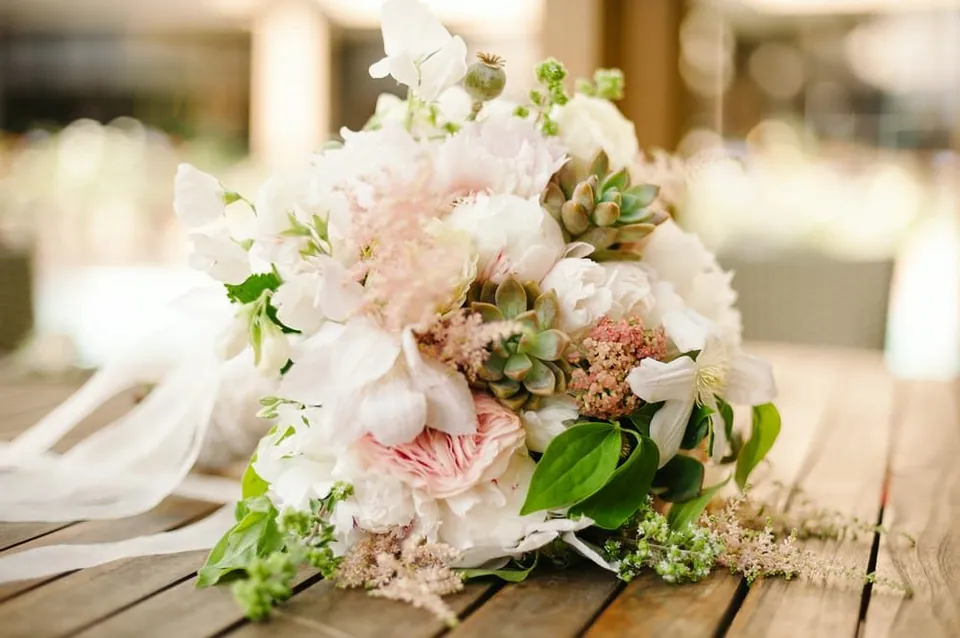 White and blush wedding flowers on a rustic table.